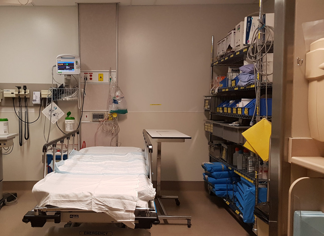 Un lit d'hôpital vide. Autour se trouvent de nombreuses machines médicales.