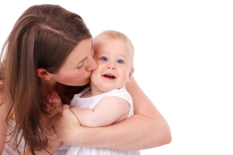 Une jeune mère embrasse son bébé.