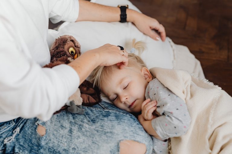 Une femme caresse la tête de son petit enfant, qui dort contre elle.