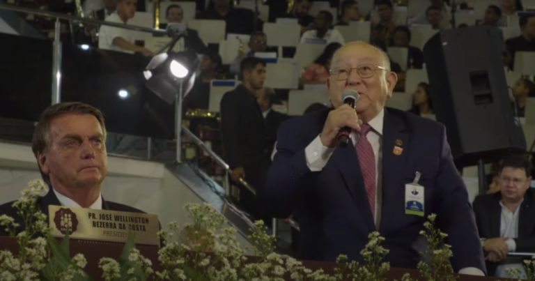 José Wellington parle dans un micro, près de Jair Bolsonaro qui est assis à sa gauche.