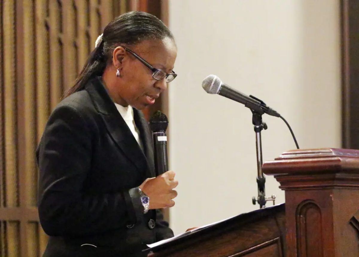 La révérende noire américaine Kathlyn Barrett-Layne parle dans un micro, derrière une chaire