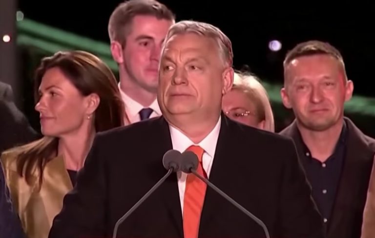 Viktor Orbán se tient derrière un micro. Derrière lui, ses partisans se pressent.