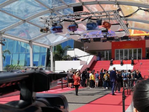 Des journalistes sont rassemblés sur le tapis rouge du Festival de Cannes, au pied des marches.