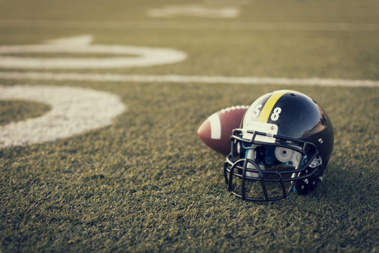 Un casque et un ballon de football américain sont posés sur la pelouse d'un stade.