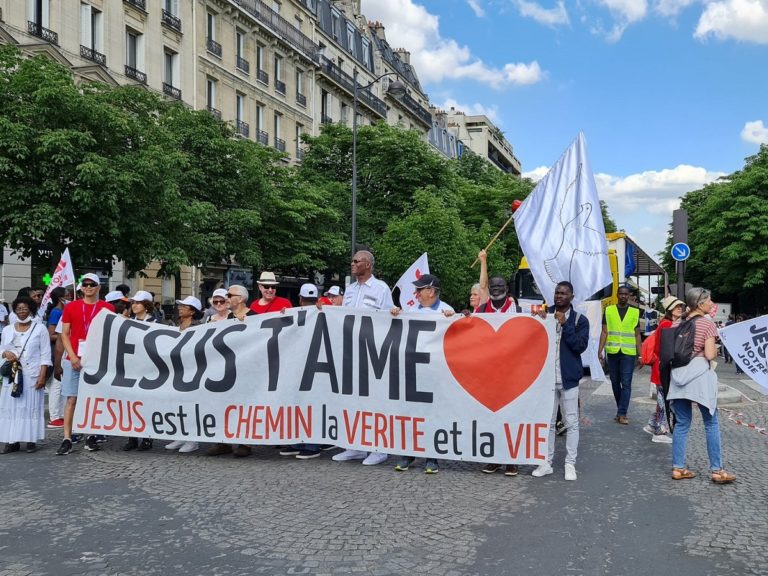 Des hommes et des femmes tiennent une bannière avec l'inscription "Jésus t'aime, Jésus est le CHEMIN, la VERITE et la VIE"