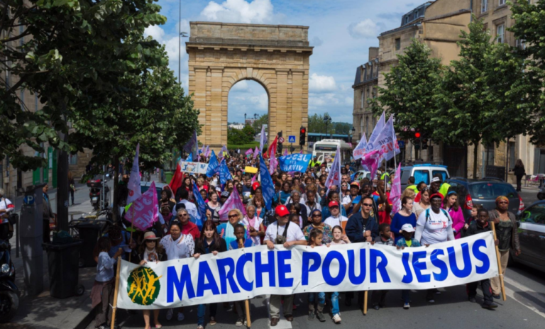 Une foule s'avance sur l'avenue des champs Elysées. Ceux en tête du cortège tiennent une longue banderole où il est écrit: "Marche pour Jésus"