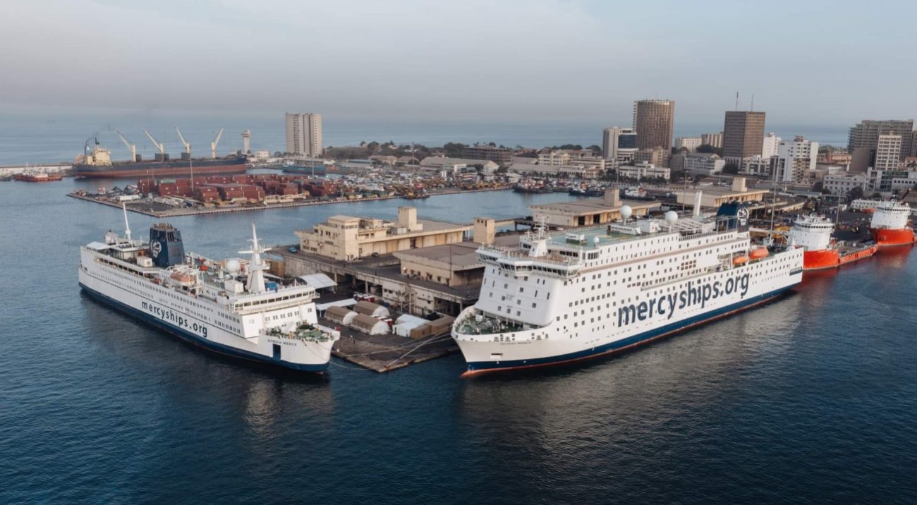 Les deux navires de Mercy Ships accostés au port. Ils sont perpendiculaires l'un à l'autre.