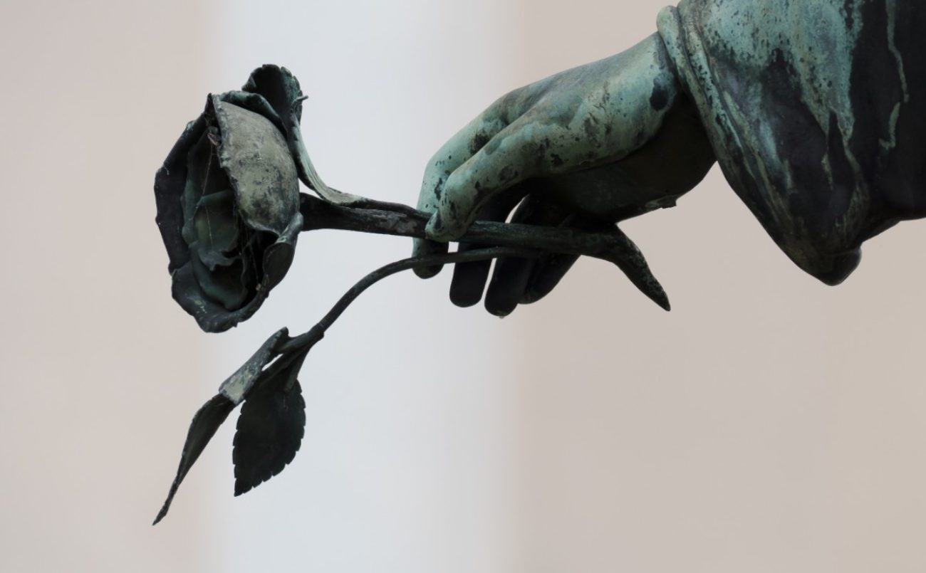 Photo de la main d'une statue tenant une rose.