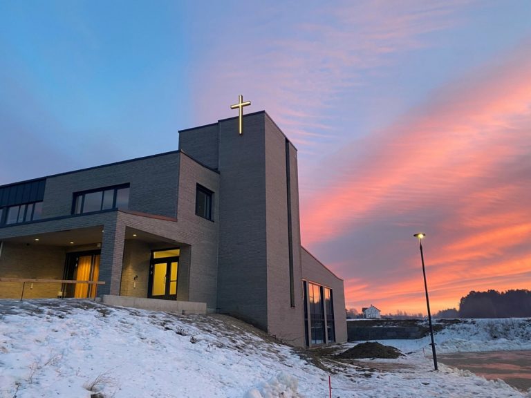 Le bâtiment d'une Eglise entourée de neige avec une croix lumineuse à son sommet