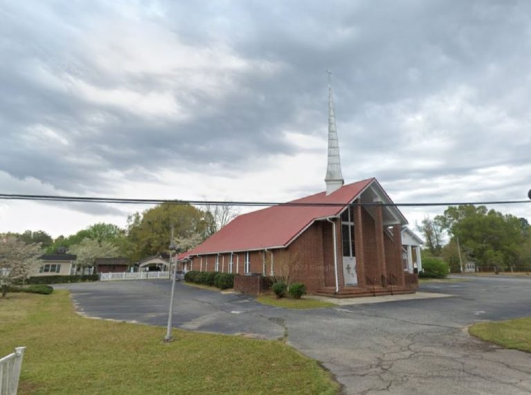 Photo de l'église baptiste de Hope Mills, avec une croix à son sommet. Le bâtiment n'est pas très grand, et il est situé en campagne.