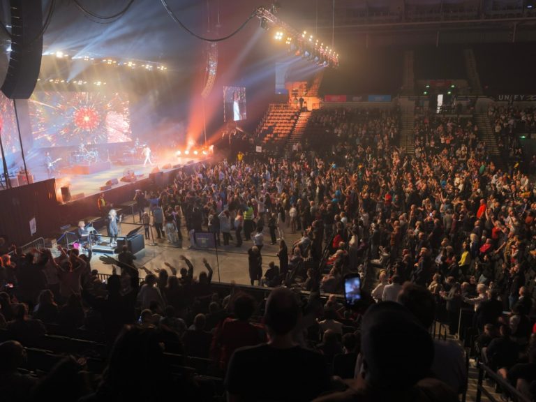 Une foule se tient debout une immense salle, à l'écoute de Franklin Graham.