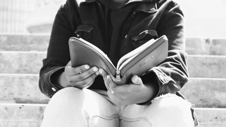 Un homme ouvre une Bible, assis sur des marches