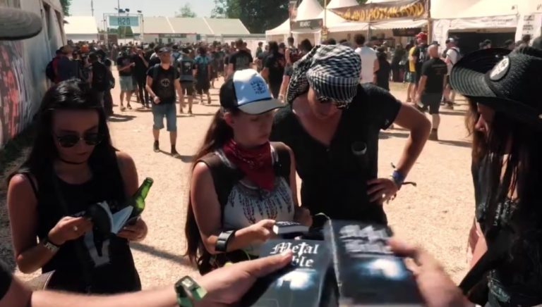 Des passants s'arrêtent pour regarder des bibles que leur tend l'équipe de Metal Mission lors d'un festival