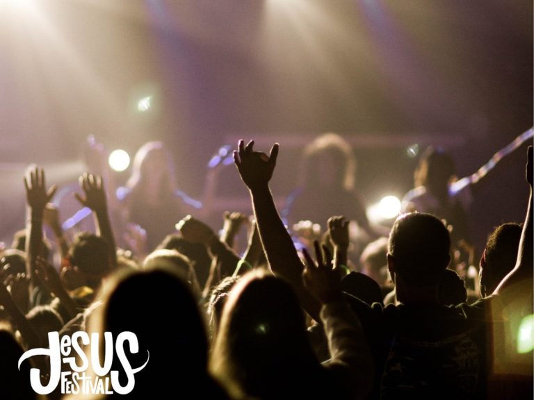 Une foule dans une salle de concert les bras en l'air