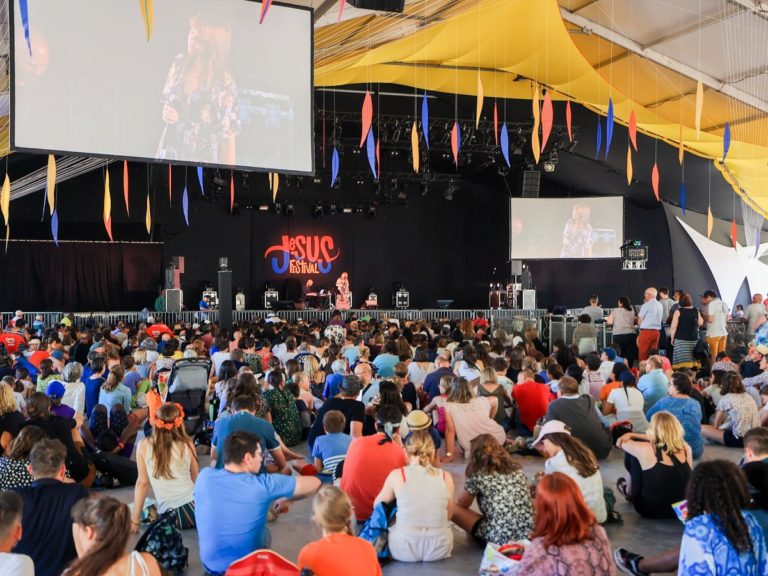 Des festivaliers assis devant la scène du Jésus Festival