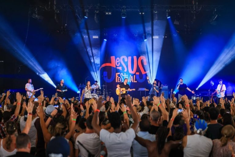 Des chrétiens debout les bras levés devant la scène éclairée du Jesus Festival