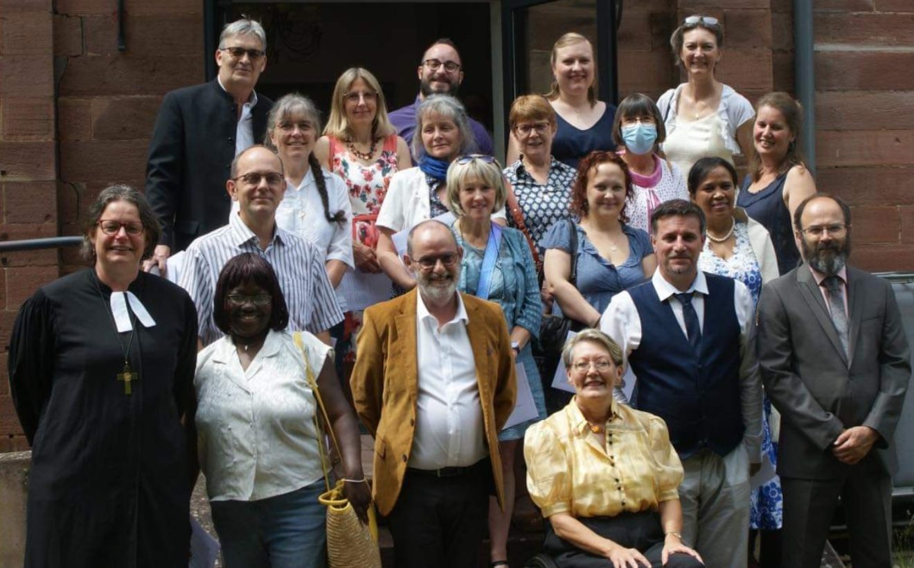 L'équipe des 18 ministres, d'âges variés, pose avec deux pasteurs de l'UEPAL, sur un perron.