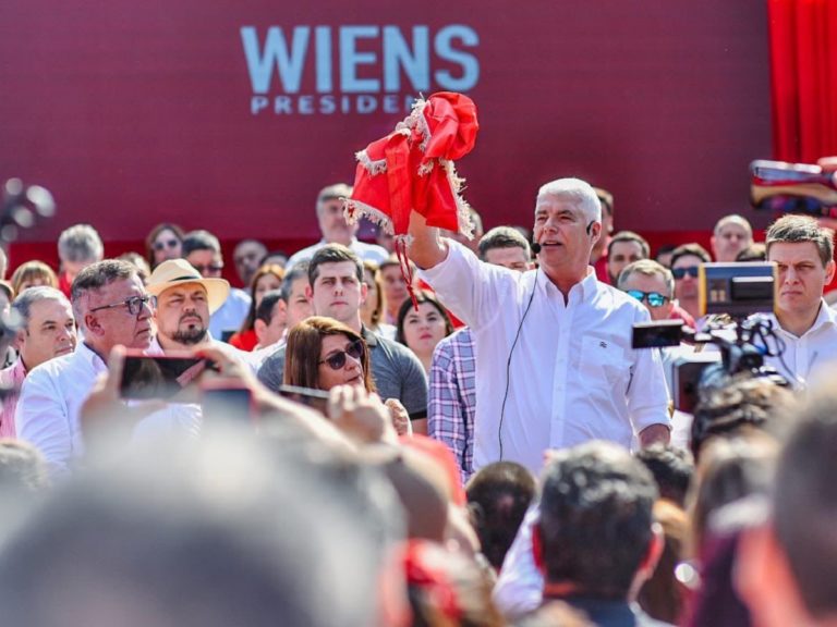 un homme tient un drapeau rouge dans la main durant un meeting politique devant la foule