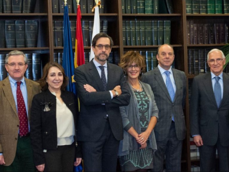 les membres du Comité de bioéthique d'Espagne devant une bibliothèque et des drapeaux officiels