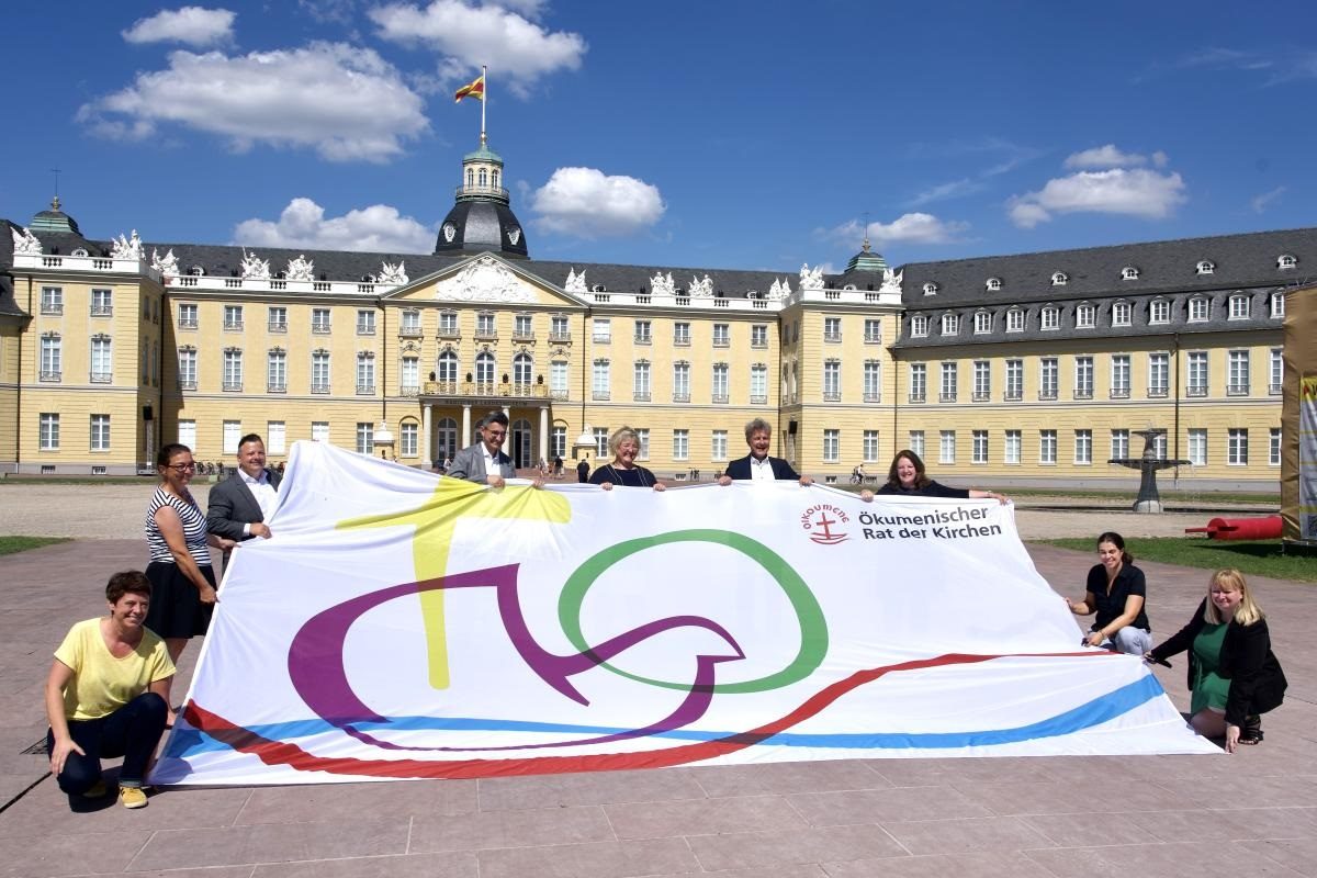 des chrétiens tiennent le drapeau du Conseil œcuménique des Eglises devant la mairie de Karlsruhe