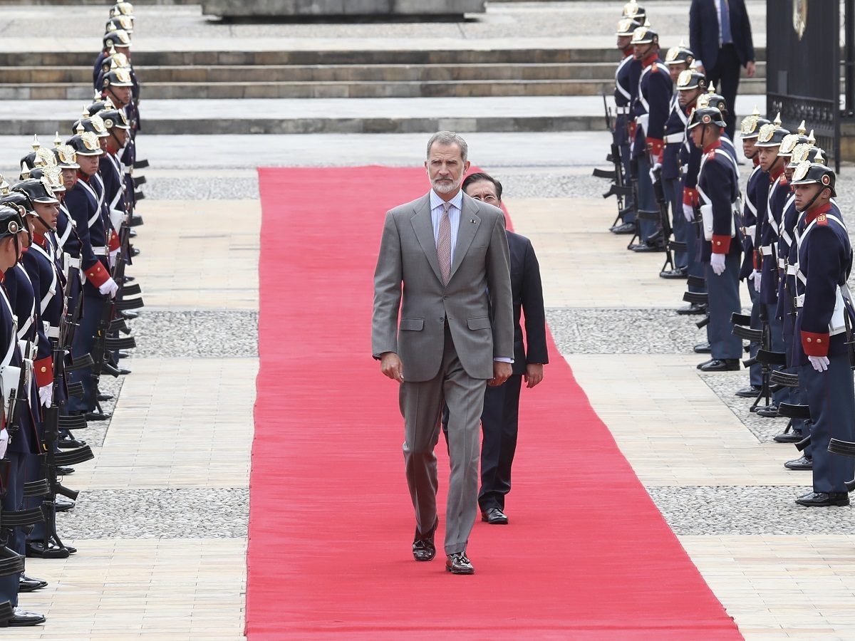 le roi marche sur un tapis rouge, devant des soldats