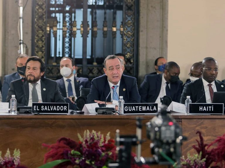 le vice-président du Salvador assis devant une pancarte El Salvador lors d'un Ccongrès politique à côté d'un représentant du Guatemala et de Haîti
