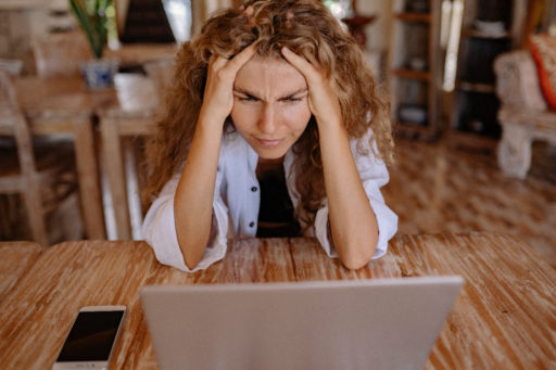 Une femme regarde un écran d'ordinateur en se tenant la tête. Elle semble chercher à comprendre ce qu'elle voit.