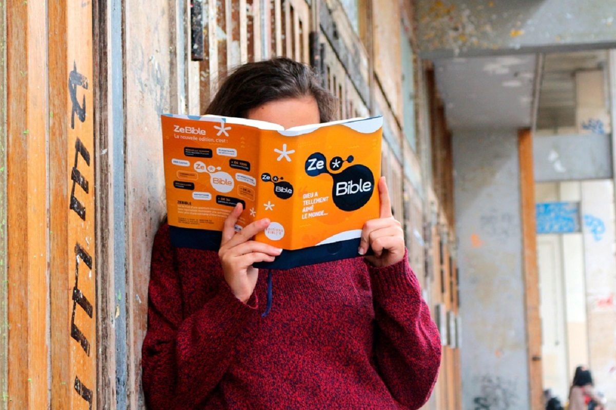 une jeune fille debout lit la ZeBible, un ouvrage destiné aux 15-25 ans