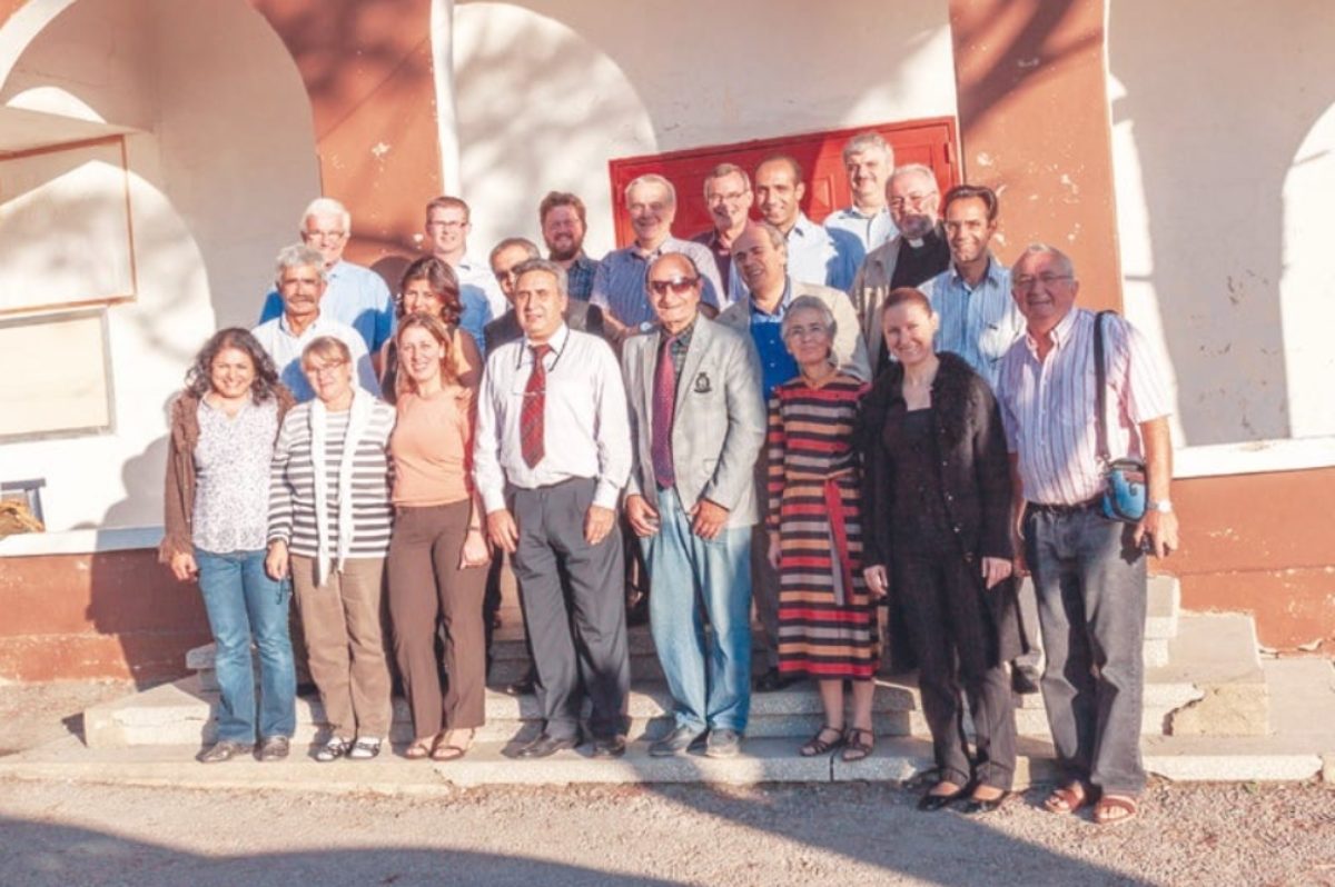 Une vingtaine de personnes prend la pose en souriant sur les marches d'un bâtiment