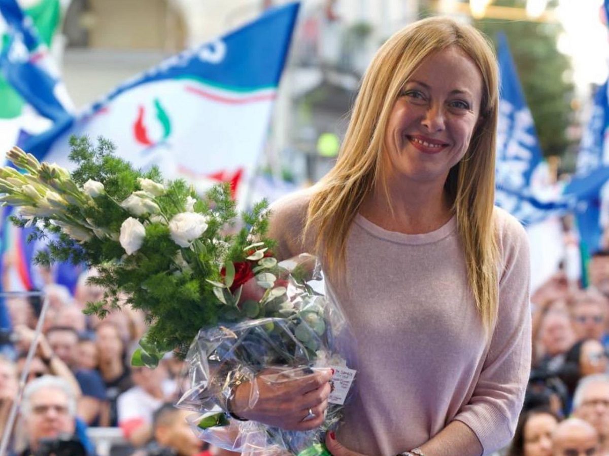 Giorgia Melonia avec un bouquet de fleurs devant des militants