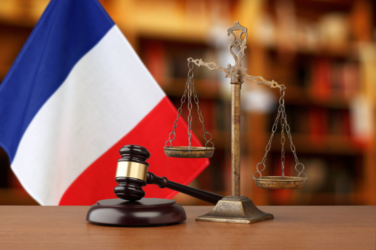 Une petite balance et un marteau de juge symbolisent la justice sur le fond d'un drapeau français