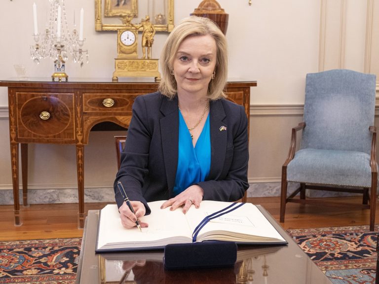 Liz Truss en train de signer un document dans un bureau