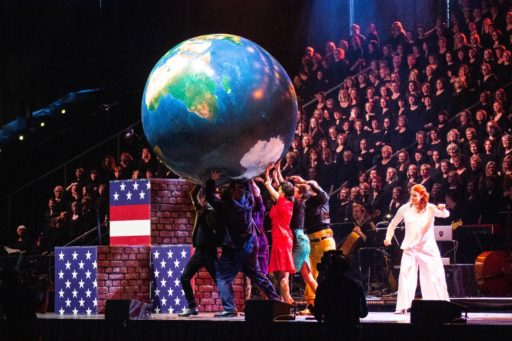 Sur scène, un groupe de comédiens portent un gros globe terrestre