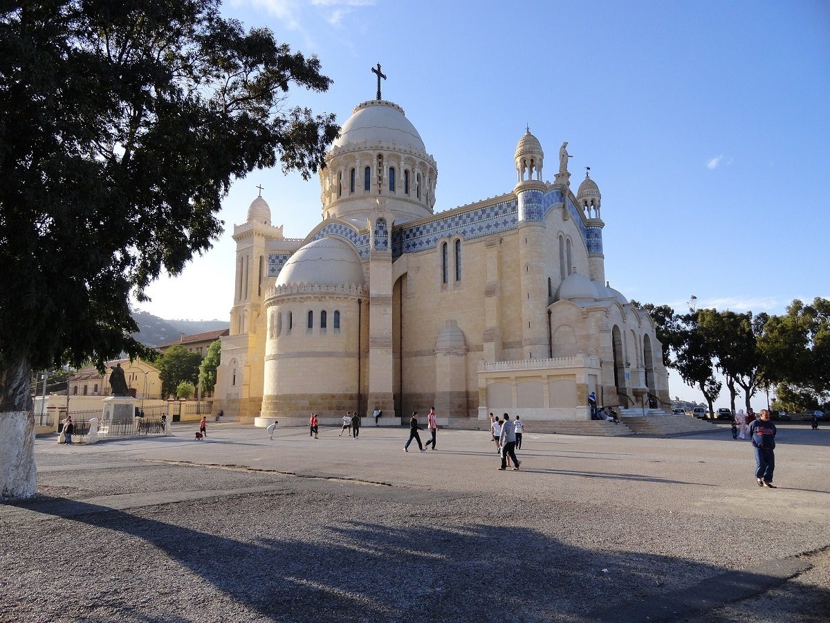 des passants marchent devant une imposante église à Alger