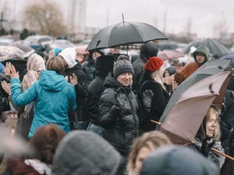 parapluie en main, des chrétiens se réunissent dans la rue pour célébrer un culte en Biélorussie