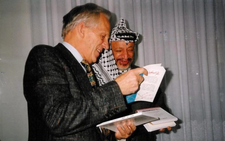 Frère André donne de la littérature chrétienne à Yasser Arafat. Les deux hommes sont joyeux.