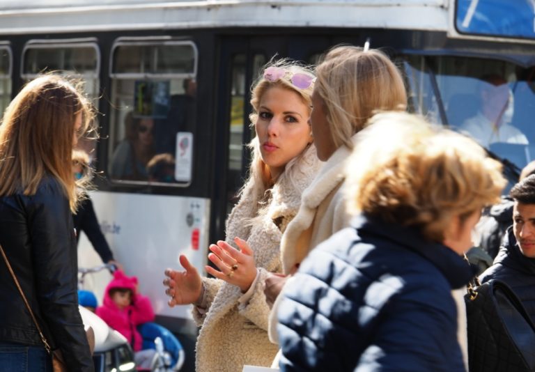 Des jeunes femmes discutent dans une rue, au milieu des passants.