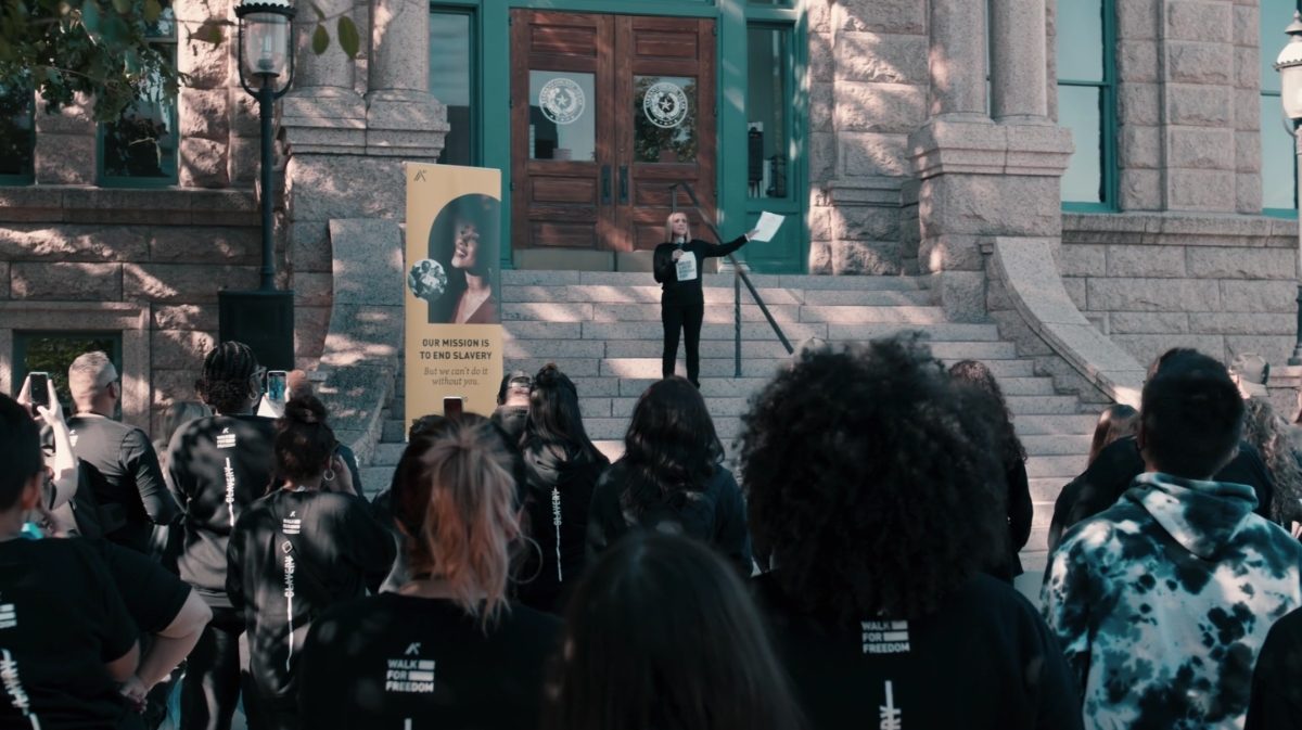 Une foule écoute une dame qui donne des instructions avant une marche pour la liberté en ville.