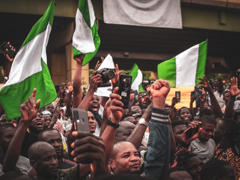 des dizaines de manifestants poing en l'air avec des drapeaux vert et blanc