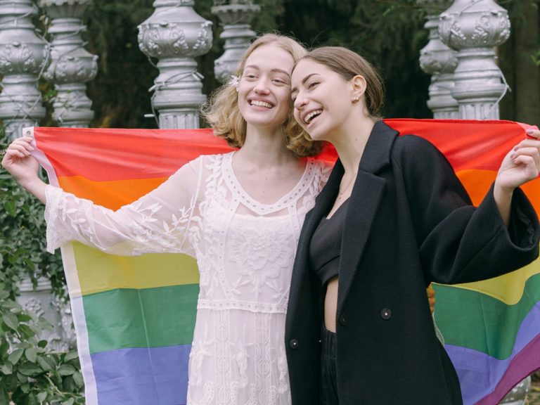 un couple de femmes avec un drapeau LGBT arc-en-ciel dans le dos