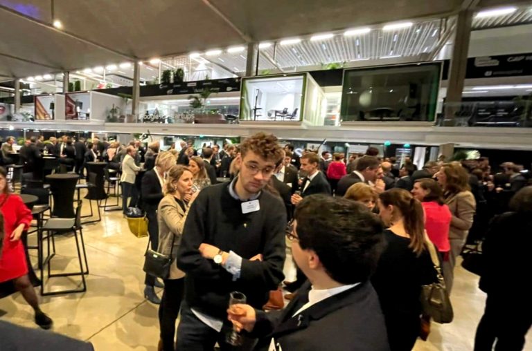 Dans une vaste salle, une foule de personnes levée discutent en groupe