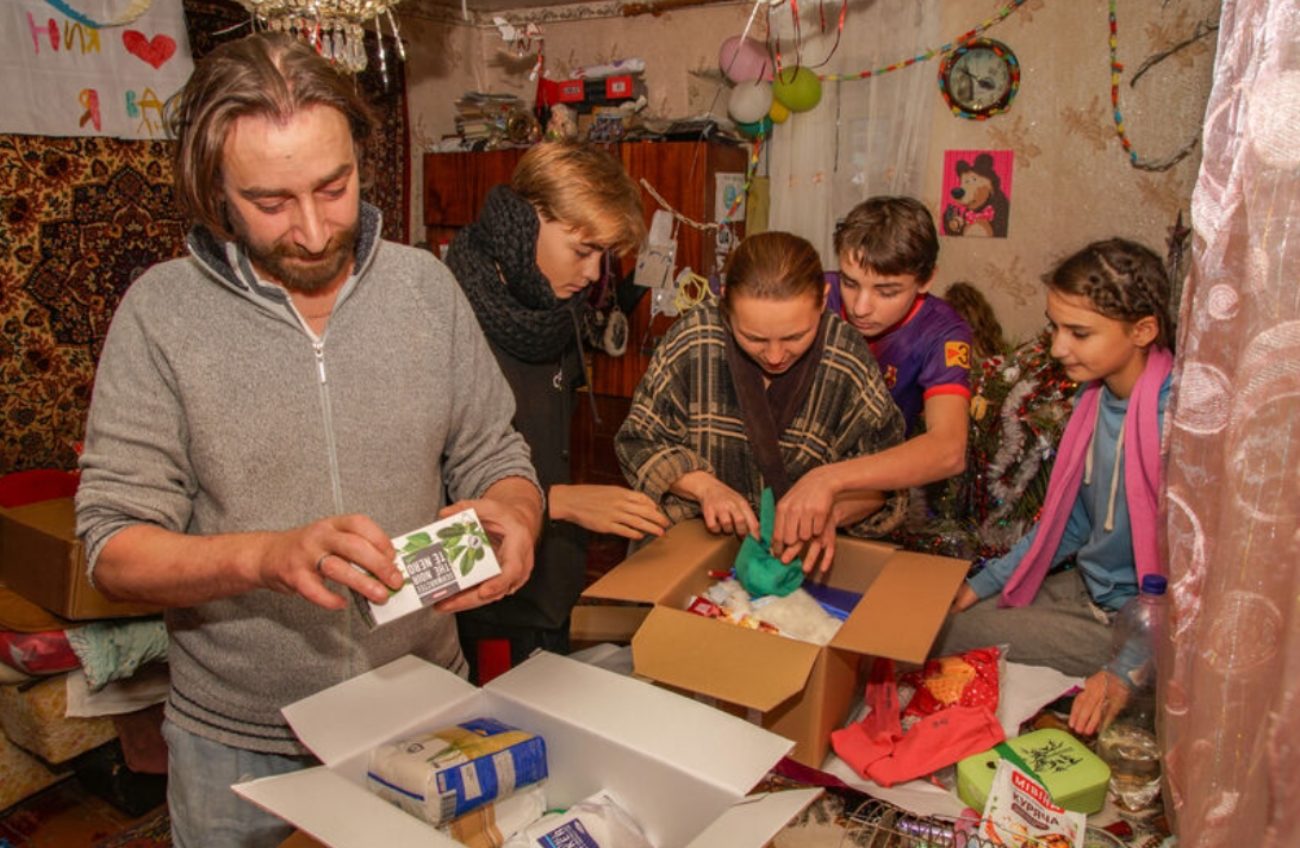 Un père et ses enfants déballent des colis.