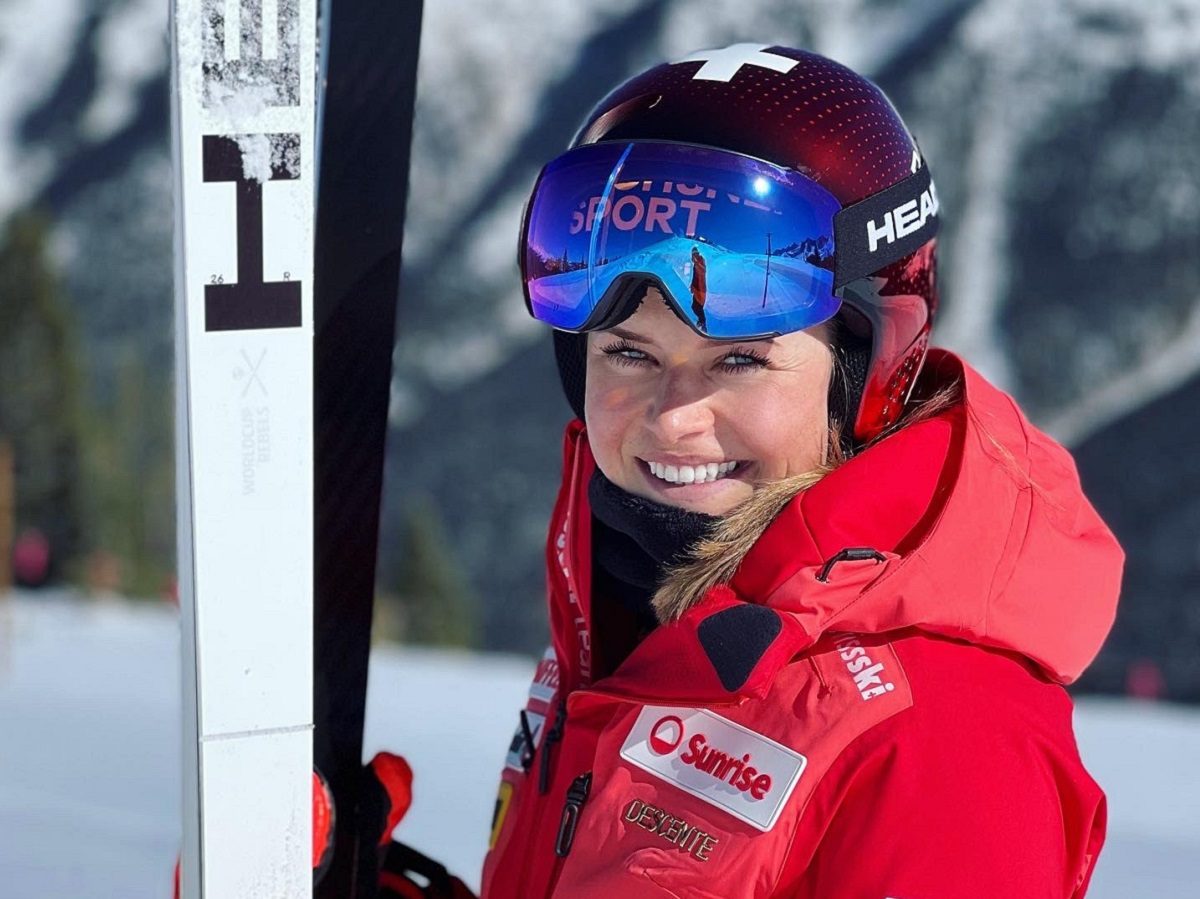Corinne Suter, skieuse suisse, avec une veste rouge et des skis blancs