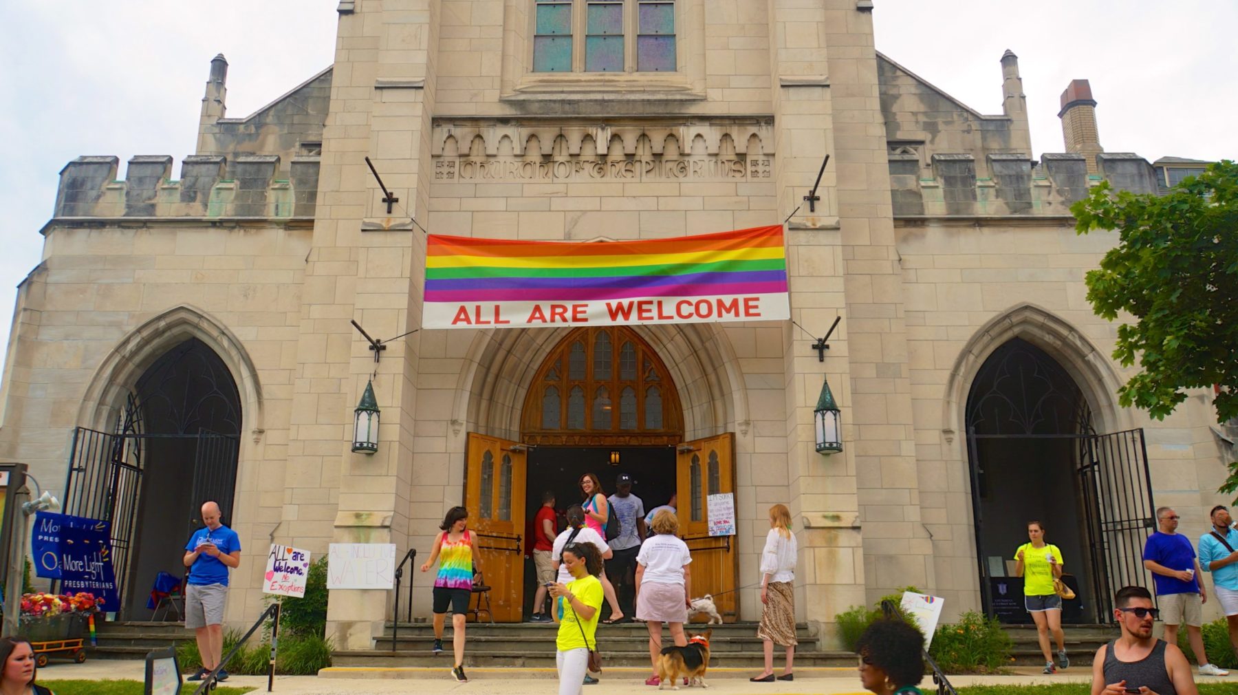 Des personnes entrent et sortent d'une église portant un drapeau LGBT