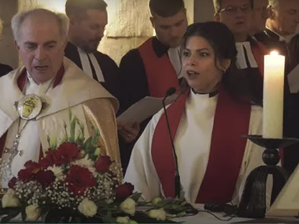 Sally Azar debout derrière un autel, à côté d'un pasteur