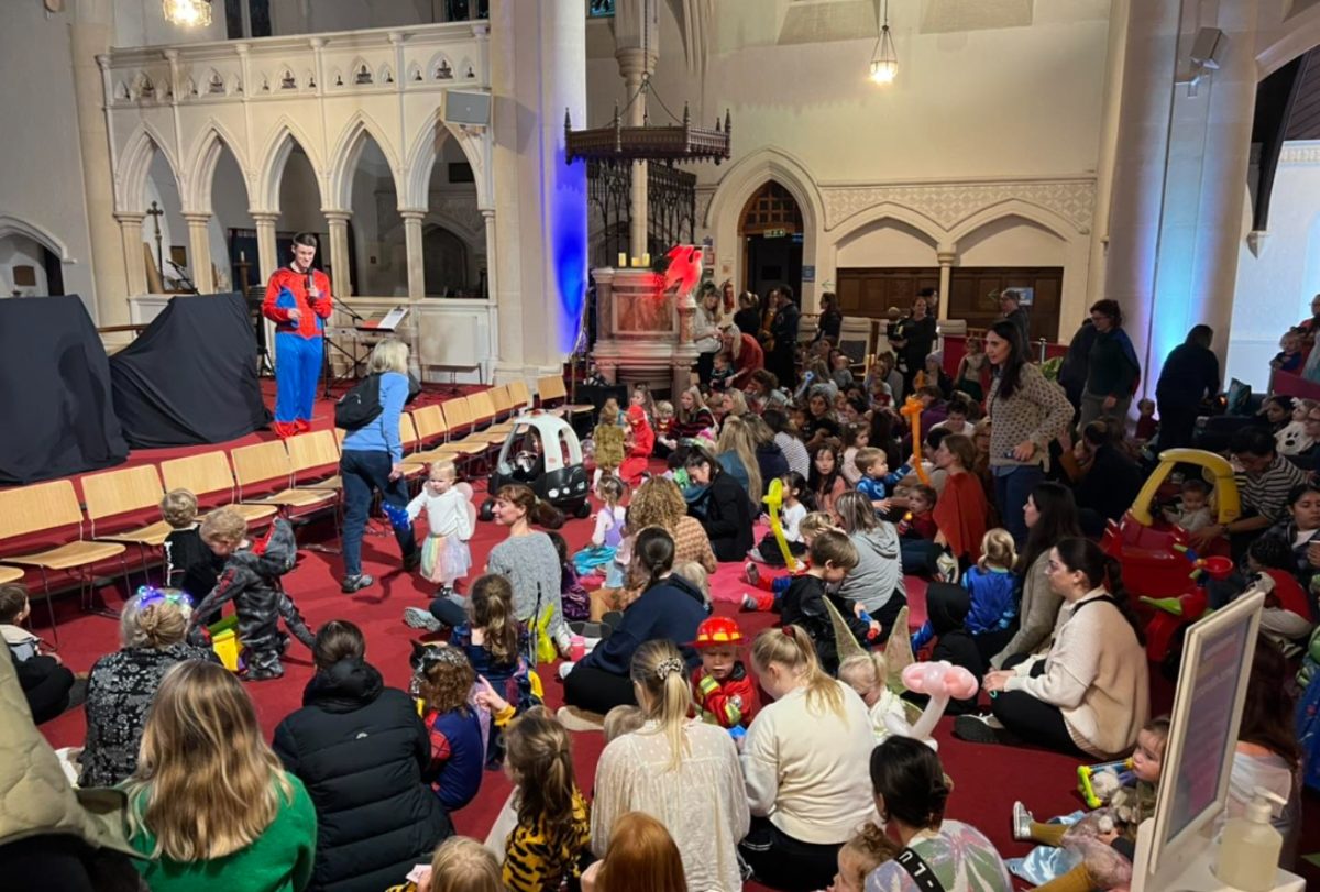 De nombreux parents sont assis sur la moquette avec leurs enfants, au pied de la scène lors d'un culte "Bubble Church"