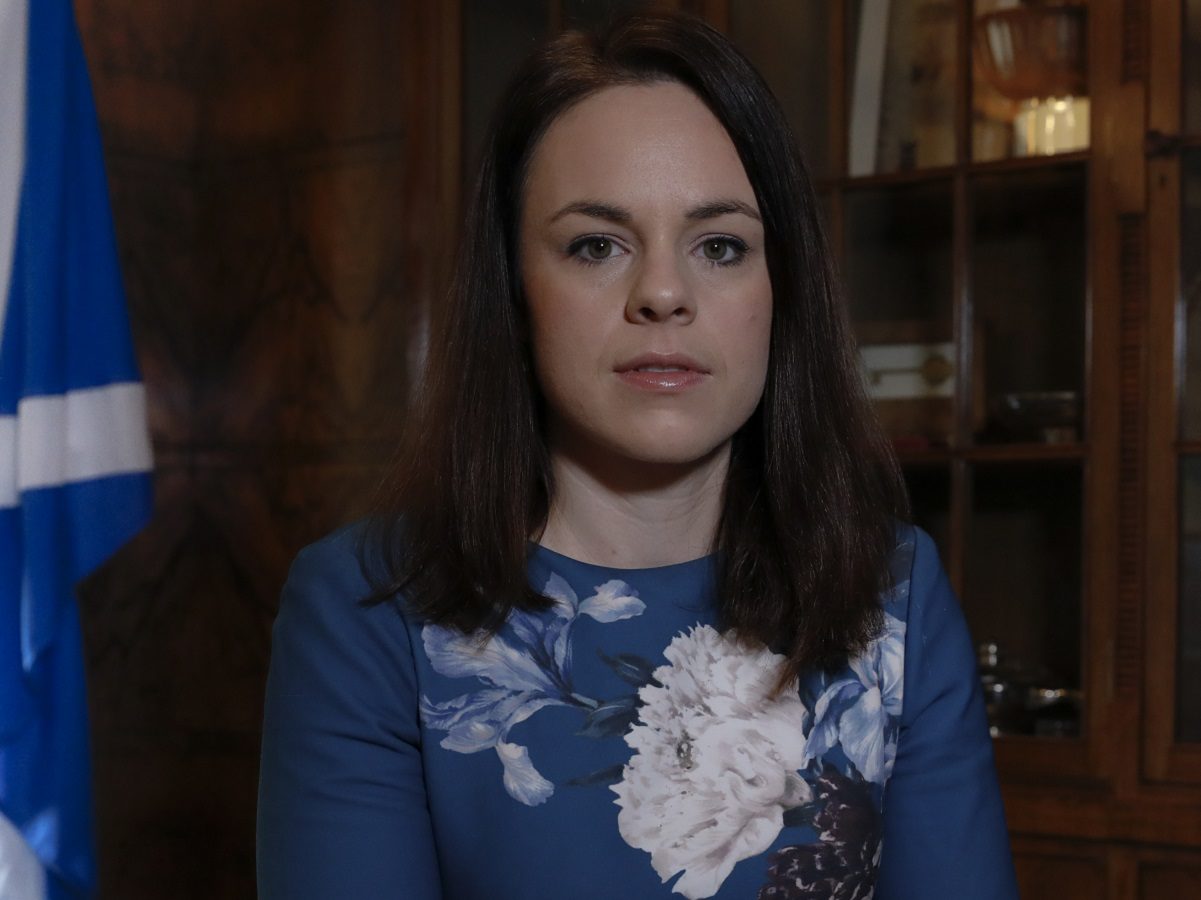 Kate Forbes devant une bibliothèque et un drapeau écossais