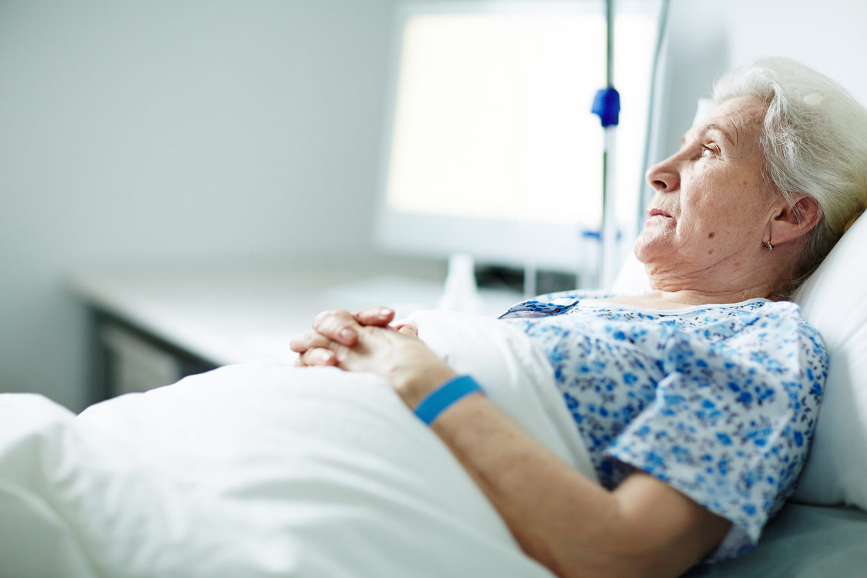 Une dame âgé, couchée sur un lit d'hôpital, semble attendre