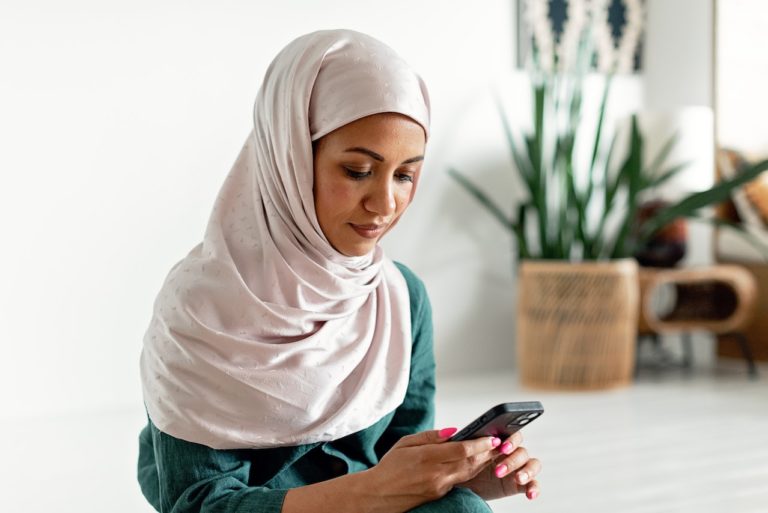 Une jeune femme consulte son smartphone chez elle