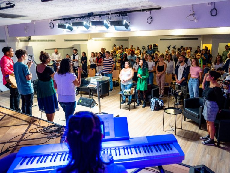 Debouts, les membres de l'Eglise adventiste de Genève participent à un temps de louange